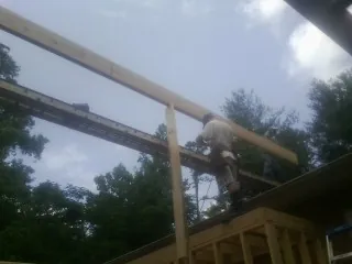 Carpenter setting a ridge beam over a new addition frame — Ice Dam Removal by Roofing Brothers in Denison