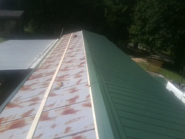 Old rusted panels beside newly installed green metal roofing — Wind Damage Roof Repair by Roofing Brothers in Denison