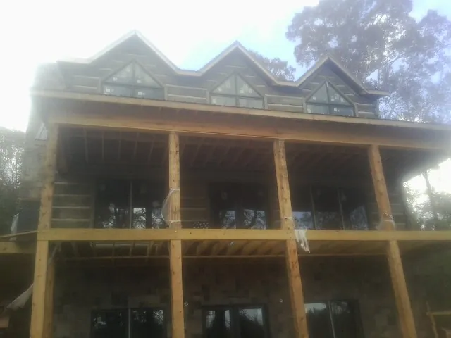 Dormers and porch framing on a large log home under construction — Roof Coating work by our crew in Denison
