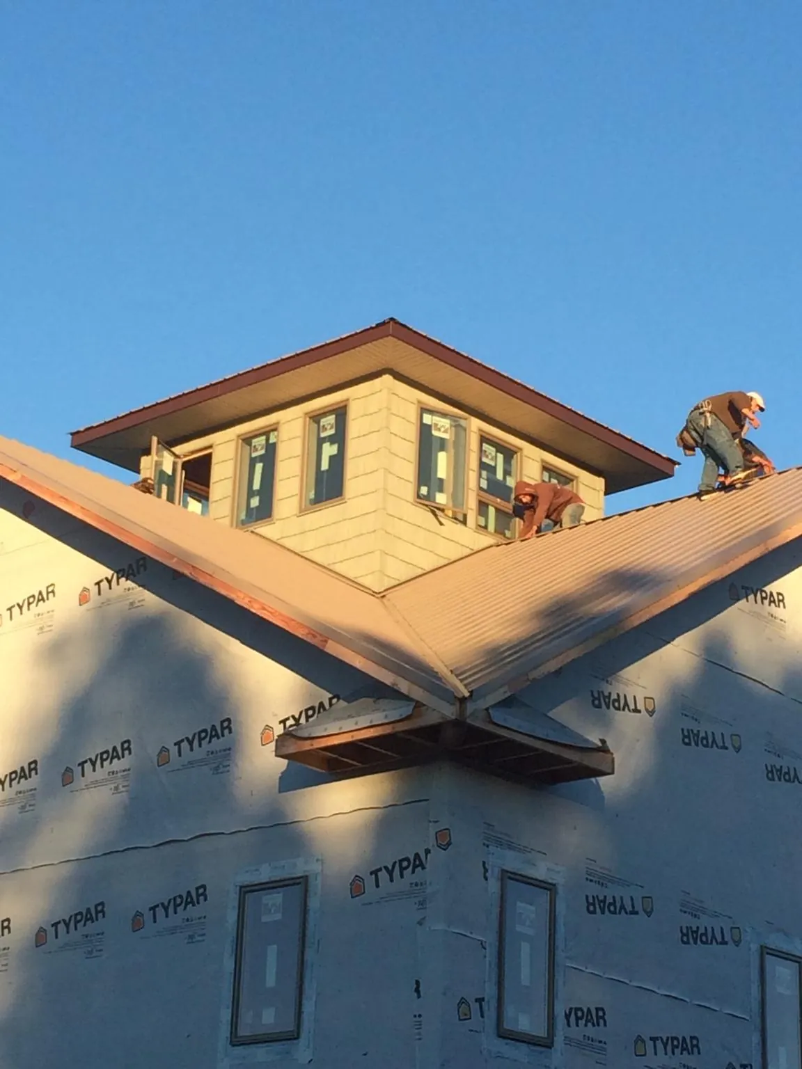 Roofers working around a rooftop cupola on a new metal roof at sunset — Roof Waterproofing in Denison by Roofing Brothers